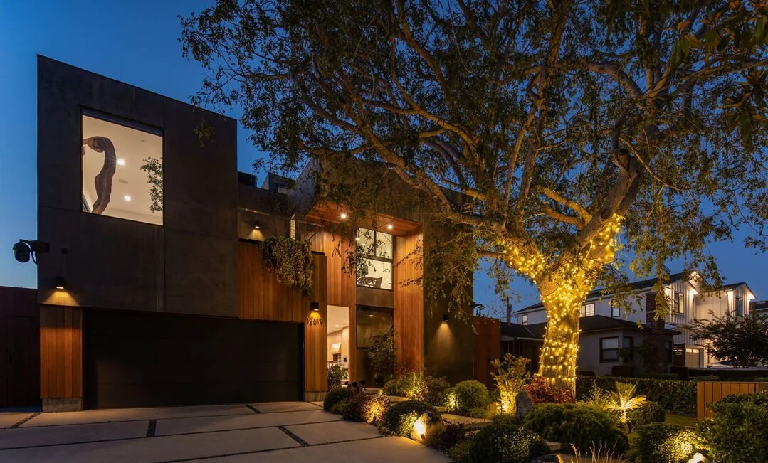 Concrete and wood facade under a large tree at night