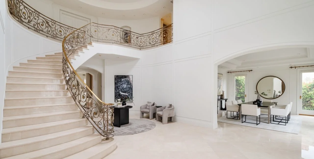 Entry hall with a curved stone stair and iron balustrade